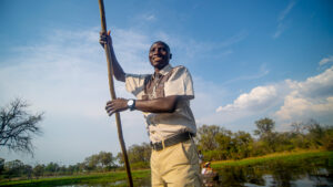 Khwai Expeditions Camp a man poling a traditional mokoro canoe in Khwai